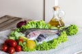 Fresh see bass and sea bream with some ingredients on green salad on wooden background Royalty Free Stock Photo