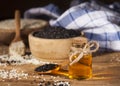 Fresh sesame oil in a glass bottle and white and black seeds in wooden bowls