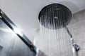 Fresh shower behind wet glass window with water drops splashing. Water running from shower head and faucet in modern bathroom Royalty Free Stock Photo
