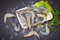 Fresh shrimp prawns for cooking with spices lemon on dark background in the seafood restaurant, raw shrimps on plate plastic tray