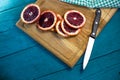 fresh sicilian orange cut into slices with a kitchen knife and a checkered tablecloth on a beautiful wooden boardd