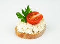 Fresh slice of baguette bread smeared with cottage cream cheese with parsley and tomato