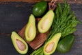 Fresh sliced avocados and dill on the wooden board. Raw ingredients for veggie healthy or diet dish on the black background Royalty Free Stock Photo