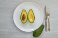 Fresh sliced avocados on the white plate. Healthy vegetarian diet food on gray background
