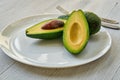 Fresh sliced avocados on the white plate ready to eat. Diet vegetarian food on the gray background