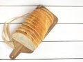 Fresh sliced bread and wheat on wooden cutting board on white wooden table, top view Royalty Free Stock Photo