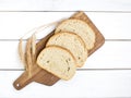 Fresh sliced bread and wheat on wooden cutting board on white wooden table, top view Royalty Free Stock Photo