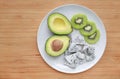 Fresh sliced fruit avocado, dragon fruit and kiwi on white plate against wooden board background with copy space Royalty Free Stock Photo