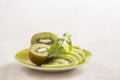 Fresh sliced kiwi on plate. Green Kiwi fruit slices on white wooden background. Copy space. Kiwi cuted on plate