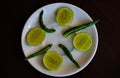 Fresh sliced lemon and green chilies on a white plate. Top view of lime half into pieces and green chilies Royalty Free Stock Photo