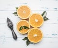 Fresh sliced oranges with leaves and wooden crush for fruit, rustic wooden background, top view Royalty Free Stock Photo