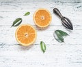 Fresh sliced oranges with leaves and wooden crush for fruit, rustic wooden background, top view, space for text Royalty Free Stock Photo