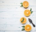 Fresh sliced oranges with leaves and wooden crush for fruit, on rustic wooden background, view, space for text Royalty Free Stock Photo