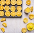 Fresh sliced oranges in a wooden box with a juicer and a glass of juice on wooden rustic background top view close up text ar Royalty Free Stock Photo