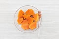 Fresh sliced papaya in glass plate with fork on gray wooden background Royalty Free Stock Photo