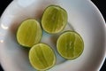 Fresh sliced pieces of lemons on a white plate. High angle of lime fruits slices in a bowl on wooden textured table Royalty Free Stock Photo