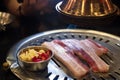 Fresh sliced pork on hot pan and chili garlic with range hood smoke Korean-Style BBQ in a Korean restaurant Royalty Free Stock Photo