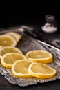 Fresh Sliced Ripe Lemons on Plate, with Salt and Knife on Black Royalty Free Stock Photo