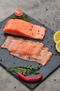 Fresh sliced salmon fillet with arugula, avocado and lemon on slate plate. Wild atlantic fish