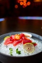Fresh sliced tuna sashimi served in bowl with ice in a restaurant. Blurred background with lights. Royalty Free Stock Photo