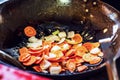 Fresh sliced vegetables: onion and carrot grilled with olive oil in pan or wok in the kitchen on hob. Concept of cooking.