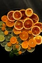 Fresh slices of citrus fruits on black round plate on black background Royalty Free Stock Photo