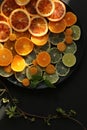 Fresh slices of citrus fruits on black round plate on black background Royalty Free Stock Photo