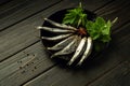 Fresh small sea fish smelt, sardine on a black background with spices and herbs. Top view. Healthy sea food concept Royalty Free Stock Photo