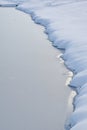 Fresh snow defines serrations of a frozen pond