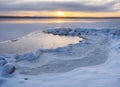 Fresh snow on the shore, lake bound by ice and snow at sunset in winter Royalty Free Stock Photo