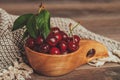 Fresh sour cherries with green leaves in wooden bowl Royalty Free Stock Photo