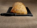 Fresh sourdough bread with nuts and a knife on a slate plate and hessian table cloth Royalty Free Stock Photo