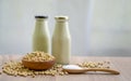 Fresh soybean seeds in brown wooden bowl with sugar in spoon and two bottles of soy milk on the table Royalty Free Stock Photo