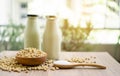 Fresh soybean seeds in brown wooden bowl with sugar in spoon and two bottles of soy milk on the table, under sunlight morning