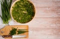 Fresh green onion feathers are cut with a knife on a cutting Board and placed on a dehydrator grid.