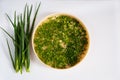 Fresh spicy spring green onion feathers are cut and placed on a dehydrator grid on a white background.