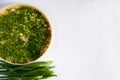 Fresh spicy spring green onion feathers are cut and placed on a dehydrator grid on a white background.