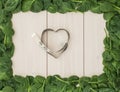 Fresh spinach leaf frame and heart shaped measure tape on wooden board. weight loss concept