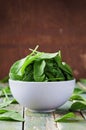 Fresh spinach leaves in bowl on rustic kitchen table Royalty Free Stock Photo