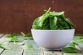 Fresh spinach leaves in bowl on rustic kitchen table Royalty Free Stock Photo