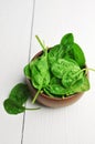 Fresh spinach leaves in wooden bowl over white wooden table. Healthy vegan food. Green living and eco-conscious concept Royalty Free Stock Photo