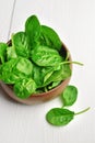 Fresh spinach leaves in wooden bowl over white wooden table. Healthy vegan food. Green living and eco-conscious concept Royalty Free Stock Photo