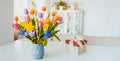 Fresh spring colorful bouquet of tulips, daffodils, irises in vase and gift box on white table with light classic design room Royalty Free Stock Photo