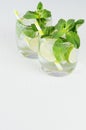 Fresh spring drink with slices lime, twig mint, ice, bubbled water, straw on soft blue wood plank, top view, copy space. Royalty Free Stock Photo