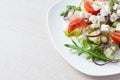 Fresh spring salad with cucumber, tomato, cheese and arugula isolated on a white plate Royalty Free Stock Photo