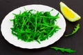 Fresh spring salad with rucola and lemon, in bowl on dark stone Royalty Free Stock Photo