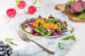 Fresh spring salad with rucola, lettuce, blueberries, radish, beet and slices of peach. White background with free text space