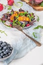 Fresh spring salad with rucola, lettuce, blueberries, radish, beet and slices of peach. White background with free text space