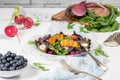 Fresh spring salad with rucola, lettuce, blueberries, radish, beet and slices of peach. White background with free text space