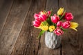 Fresh spring yellow and pink tulips bouquet in blue vase standing on rustic wooden table background. Festive flowers for Royalty Free Stock Photo